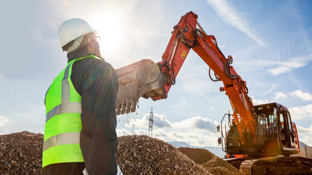 construction worker or engineer on construction site with excavator