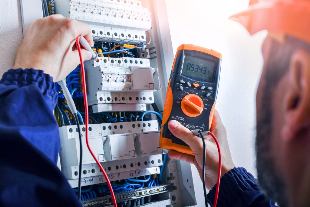 Electrician installing electric cable wires of fuse switch box.