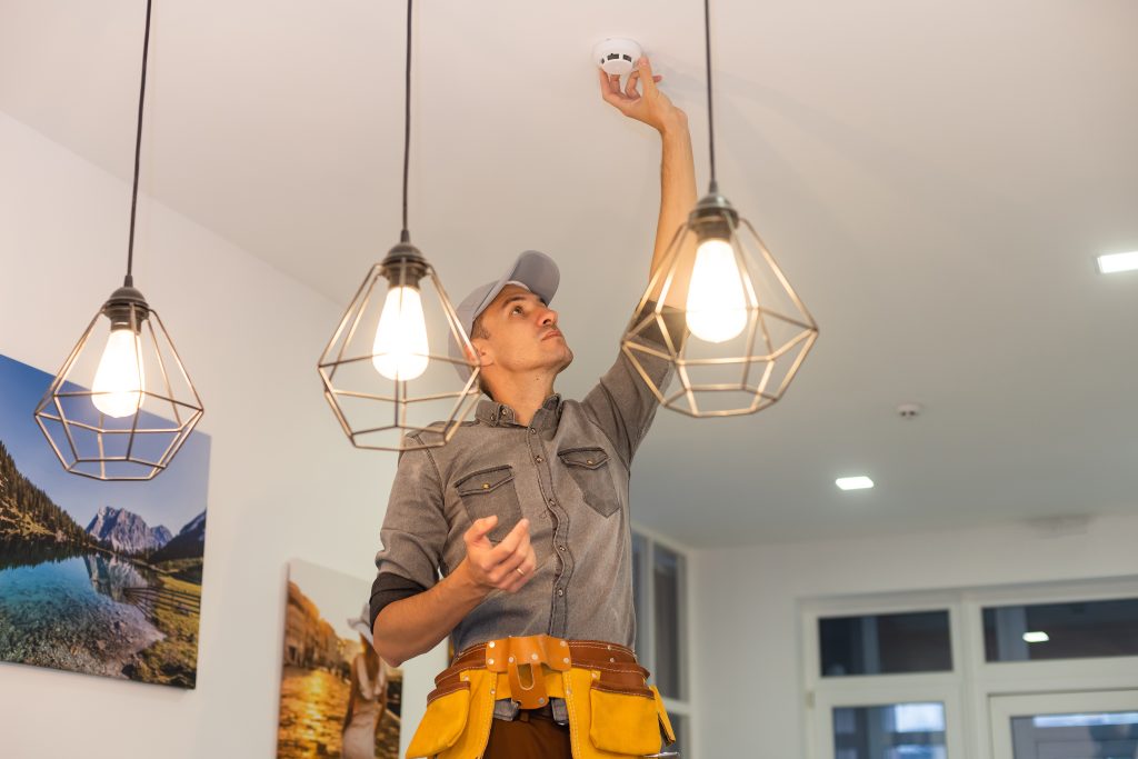 Handyman installing a smoke detector on the ceiling