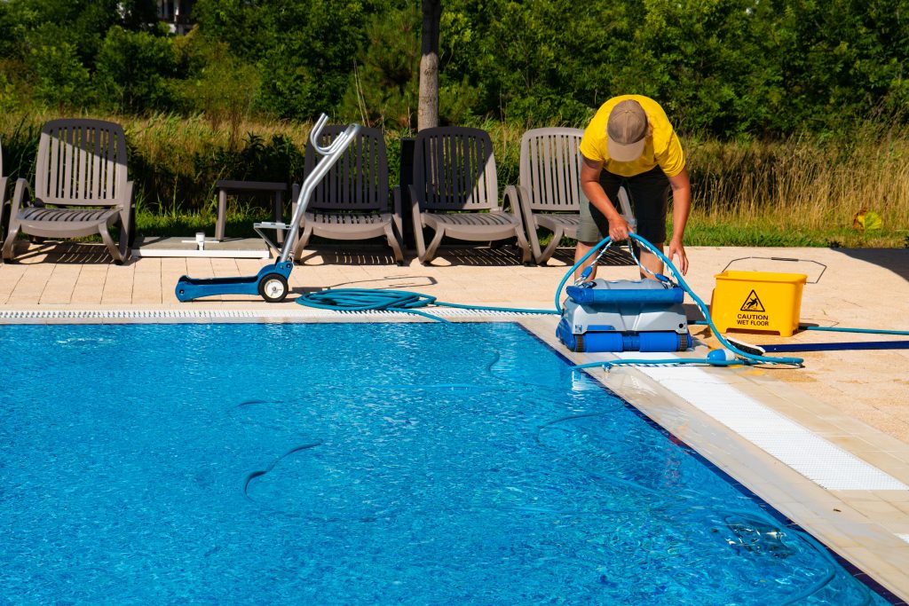 The cleaner turns on an automatic cleaning robot to clean the pool. Automatic pool cleaning. Concept photo pool cleaning, hotel staff, service.
