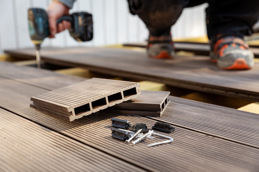wpc terrace construction - worker installing wood plastic composite decking boards